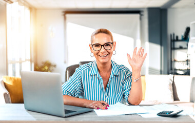 Mature blond woman with wide toothy candid smile sit on chair look at camera head shot portrait, having video call lively positive conversation with friend via online application concept.