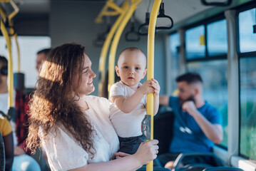 Mother holding her baby boy and riding a bus in the city