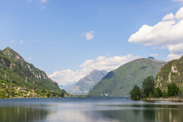Fototapeta na wymiar Light summer haze from evaporation over the waters of an alpine lake Idro(Lago d'Idro) surrounded by high rocky wooded mountains. Brescia, Lombardy, Italy
