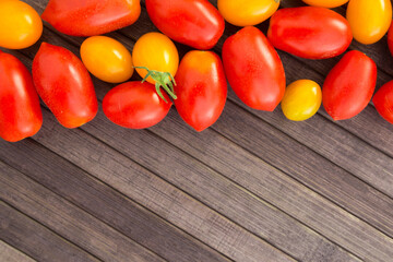 ripe appetizing yellow and red cherry tomatoes with place for inscription on wooden table