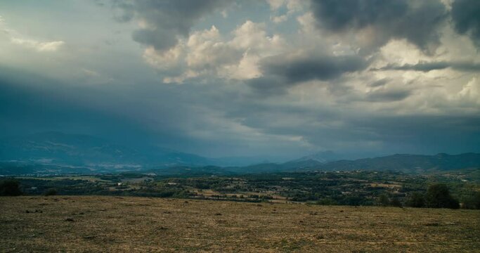 Timelapse of rural landscape view to agricultural field and mountain on horizon. Beautiful clouds moving on sky shoot in hyperlapse. 