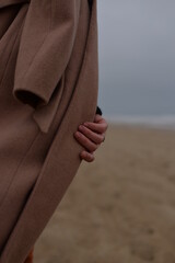 girl's hand with a ring in a coat on the seashore