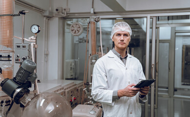 Scientist holding laptop and controlling rotational vaporizer during oil extraction. hemp oil extraction process.