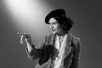 Portrait of charming woman in image of famous fashion designer posing in stylish classical clothes, jacket and hat. Black and white photography