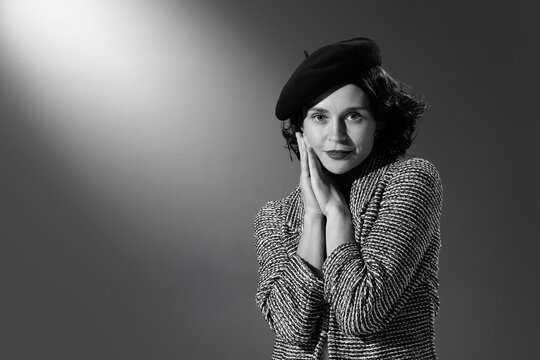 Portrait of beautiful woman in image of famous fashion designer posing in stylish classical clothes, jacket and hat. Black and white photography