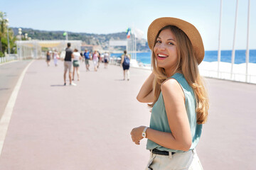 Portrait of attractive fashion woman turns around and smiling at camera walking along Promenade des...