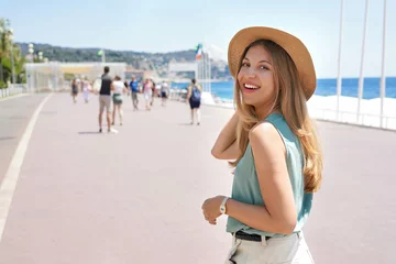 Photo sur Plexiglas Nice Portrait of attractive fashion woman turns around and smiling at camera walking along Promenade des Anglais, Nice, France
