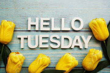 Hello Tuesday alphabet with yellow tulip flower on wooden background