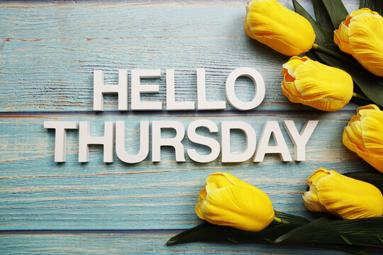 Hello Thursday alphabet with yellow tulip flower on wooden background