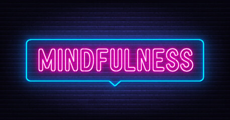 Neon lettering mindfulness on brick wall background.