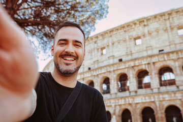 Plakat Young happy smiling caucasian man taking selfie, in front of Colosseum, Rome, Italy. Holiday, travel, vacation, tourist, summer concept.
