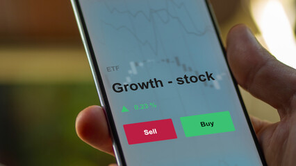 An investor's analyzing the growth - stock etf fund on a screen. A phone shows the prices of Growth - stock
