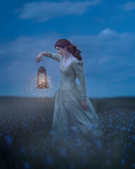 A girl with an oil lantern walks through an evening field