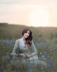 Tender girl with a bouquet of flowers in a summer field