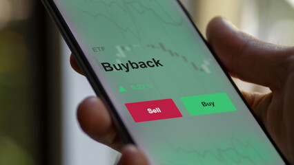 An investor's analyzing the buyback etf fund on a screen. A phone shows the prices of buy-back,...