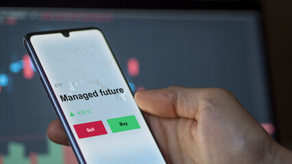 An investor's analyzing the managed future etf fund on a screen. A phone shows the prices of Managed future