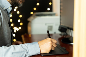 Young graphic designer sitting at his workspace using digital graphics tablet. Working professional. Freelance.