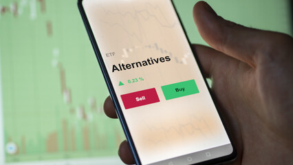 An investor's analyzing the alternatives etf fund on a screen. A phone shows the prices of alternative ETF to invest.