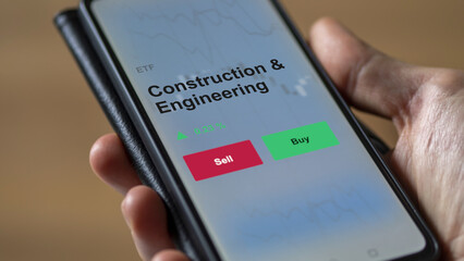 An investor's analyzing the construction & engineering etf fund on a screen to invest. A phone shows the prices of construction and engineering ETF blue chips.