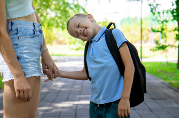 An elementary school student going to study. A first grader holds his mother's hand and smiles at...
