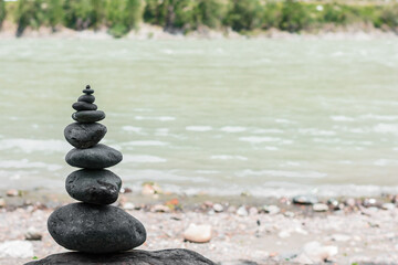 Rock balancing stones stacking by river. Stable pile or heap in soft focus with bokeh. Zen balance, minimalism, harmony and buddism