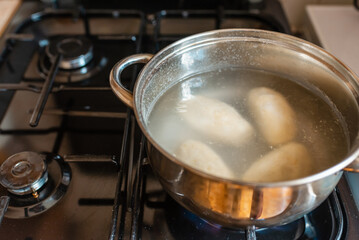 Traditional Lithuanian stuffed potato dumplings in the pot water. The dumplings are made from grated and riced potatoes and stuffed with ground meat.Indoors shot.
