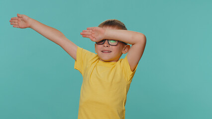 Trendy cheerful positive little toddler children boy having fun dancing and moving to rhythm, dabbing raising hands, making dubdance gesture. Young preschool kid isolated on blue studio background
