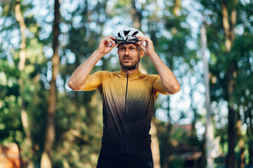 Athletic man in sport clothes riding a bike in the nature and posing with glasses