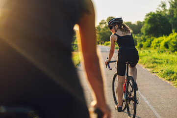 Couple riding road bicycles outside and wearing helmets and sunglasses