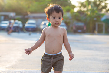 Toddler 2 year asian boy playing outdoor activity and running sunset light