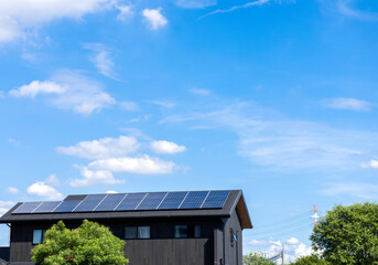 太陽光パネルが設置された住宅の屋根と快晴の青空。