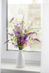 summer bouquet on white windowsill witrh  rain drops