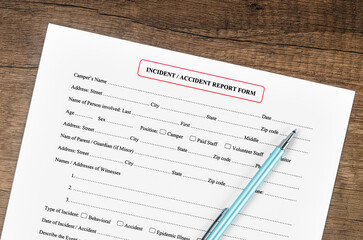 The Accident report form with pen on wooden background.