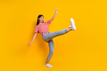 Full size portrait of ecstatic glad girl raise leg have good mood dancing isolated on yellow color...