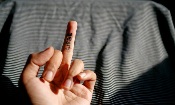Close up hand showing middle finger up with word liebe written on it