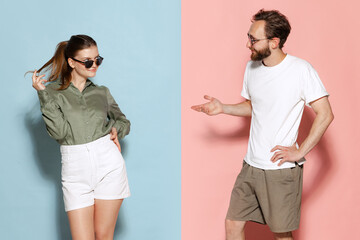 Fashionable couple, handsome man and charming girl posing isolated over blue-pink background. Fashion, emotions, youth, love, travel, vacation concept