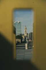 Vertical shot of a cityscape with clock tower and passers-by