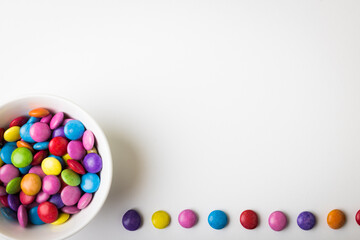 Directly above view of copy space by colorful candy trail and in bowl on white background - Powered by Adobe