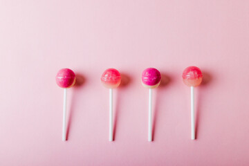 Overhead view of lollipops arranged side by side with copy space on pink background - Powered by Adobe