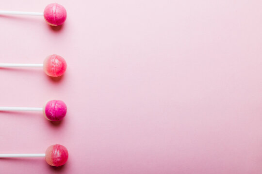 Directly above view of lollipops arranged side by side with copy space over pink background