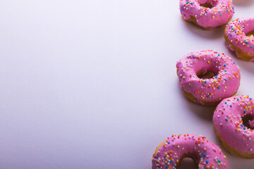 High angle view of fresh pink donuts with sprinklers by copy space on white background