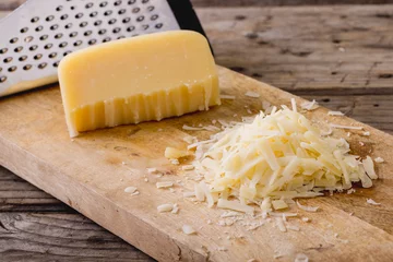 Poster Close-up of grated cheese with grater on wooden board, copy space © WavebreakMediaMicro