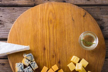 Foto op Canvas Overhead view of various cheese with rosemary on wooden board, copy space © wavebreak3