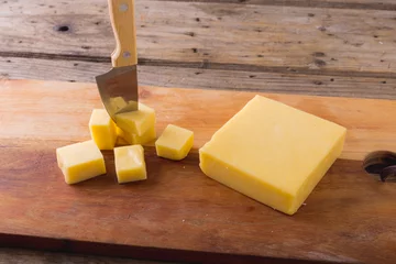Tuinposter High angle view of cheese with knife on board at table, copy space © WavebreakMediaMicro