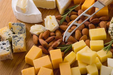 Fotobehang Close-up of various cheese with almonds and knife on wooden board, copy space © WavebreakMediaMicro