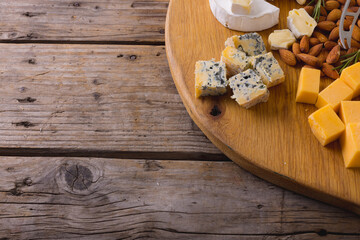 High angle view of various cheese with almonds on table, copy space