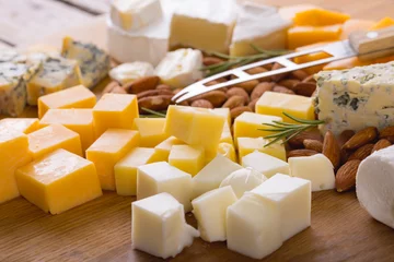 Rolgordijnen Close-up of various cheese cubes with almonds and knife on wooden board, copy space © WavebreakMediaMicro