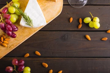 Foto op Plexiglas High angle view of cheese and grapes with almonds on wooden table, copy space © WavebreakMediaMicro