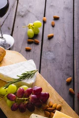 Tuinposter High angle view of cheese and grapes with almonds on wooden table, copy space © WavebreakMediaMicro
