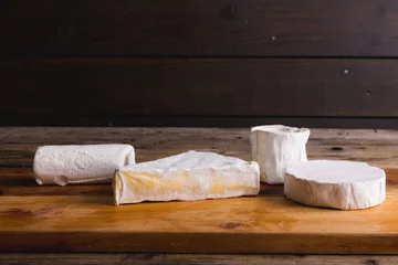 Tuinposter Brie cheese of various shape on wooden table, copy space © WavebreakMediaMicro